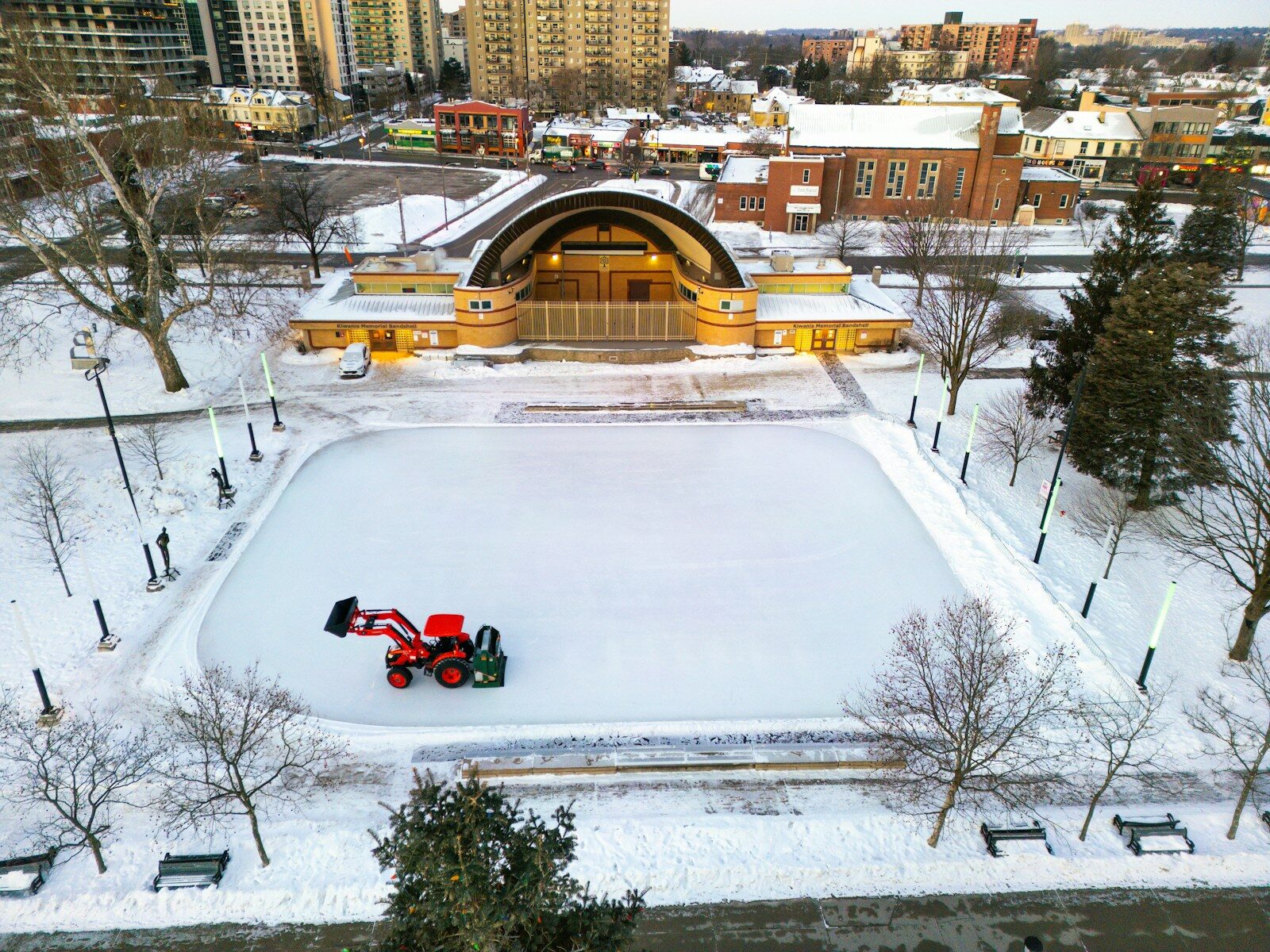 Skating rink being maintained in a snowy park.